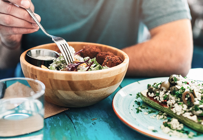 close-up of someone eating a green salad topped with legumes