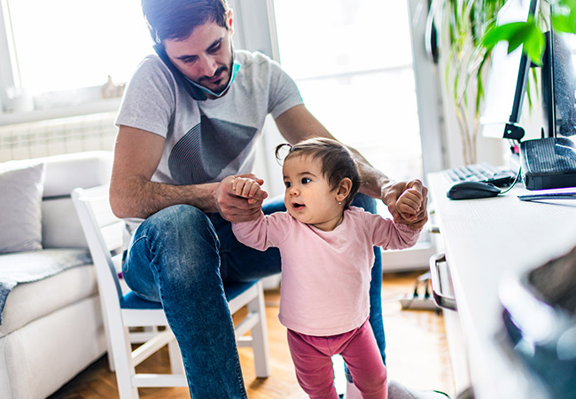 Father working from home and taking care of baby girl